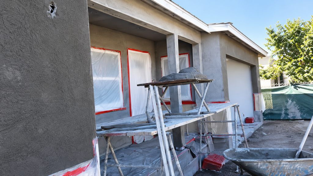 Residential exterior with stucco base coats and scaffolding